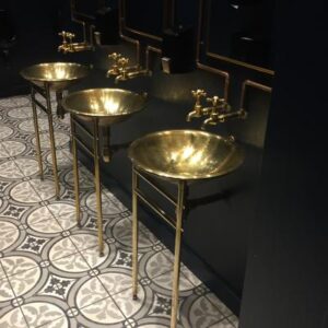 Gold bathroom sinks with black and gold fixtures in a modern bathroom setting.
