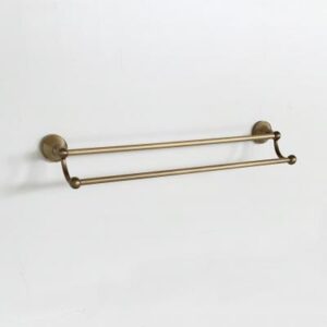 Double towel rail in brass finish mounted on a white bathroom wall, ideal for modern and elegant bathroom decor. Perfect for storing towels in style.