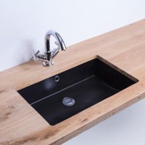 Stainless steel kitchen sink with black basin mounted in a wooden countertop for modern bathroom or kitchen decor.